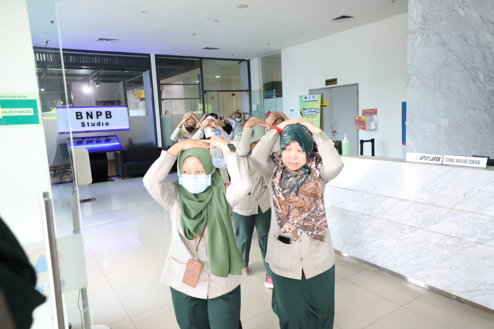 Para pegawai sedang melakukan evakuasi mandiri menuju titik kumpul, saat simulasi evakuasi bencana gempa di Gedung Graha BNPB, Jakarta pada Rabu (26/4).